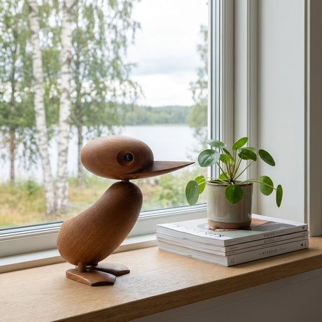 Ankfigur i teakträ placerad vid ett fönster