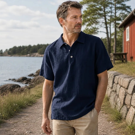 Man i marinblå linnepiké vid svensk kust.