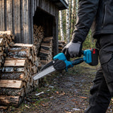 Batterimotorsåg som bärs i handtaget vid en vedbod